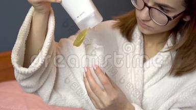 一个女人把洗发水倒进一个小罐子里。 穿着浴袍的女人拿着一罐旅行洗发水。 特写